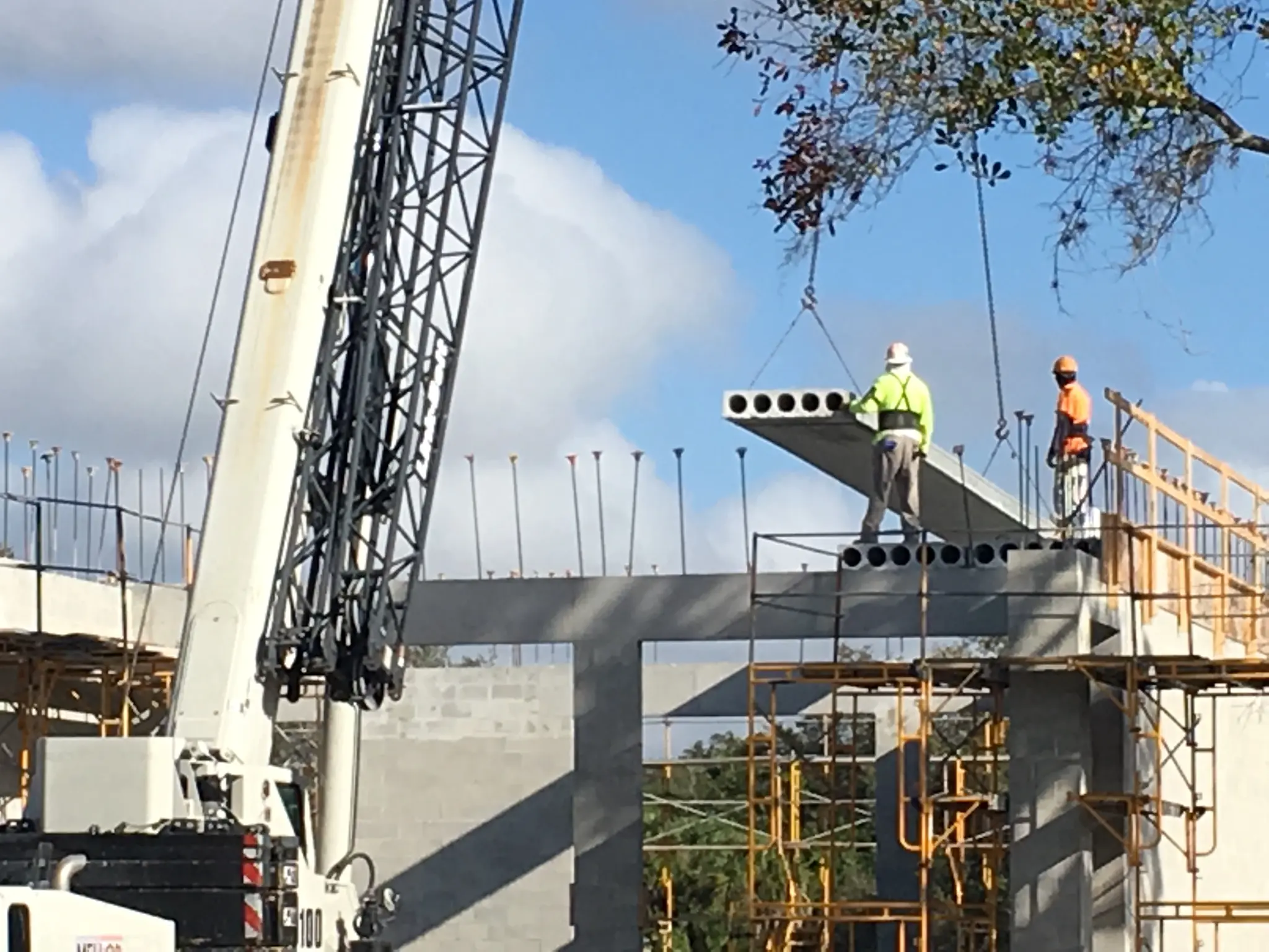 Crane setting hollowcore plank on concrete block building